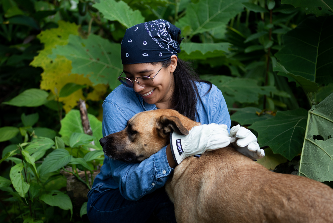Yura Sapi smiling and embracing a dog in a garden