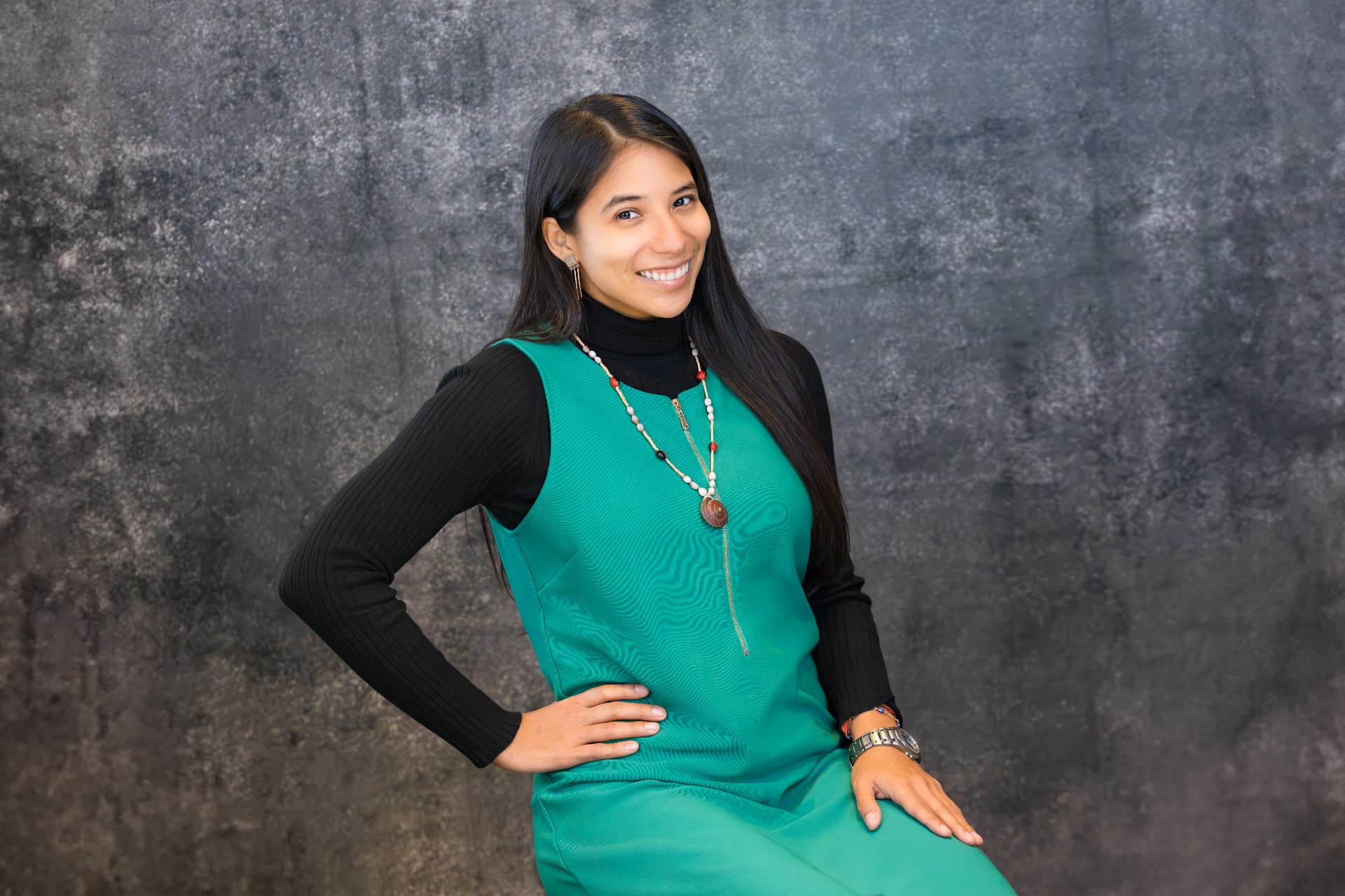 Yura Sapi in a teal outfit against a dark studio background