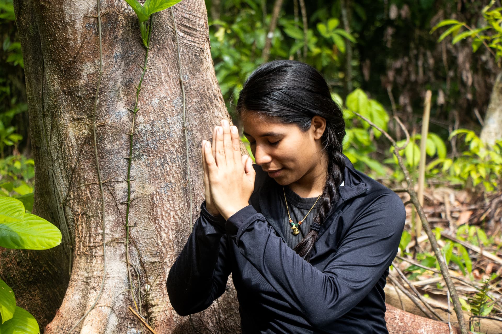 Yura Sapi with hands joined beside a tree in the forest